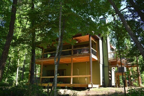 A two-story wooden cabin surrounded by trees.