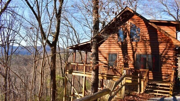 A log cabin with a wooden deck and a staircase leading to the entrance. - Falling Leaves (Blue Ridge)