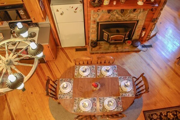 Ein Holzespeisesaal mit sechs Stühlen, einem Kamin, einem Herd und einer Chandelüster.