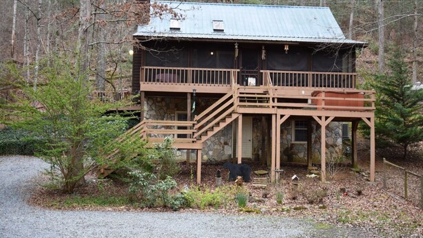 A rustic cabin with a stone foundation, wooden deck, and a metal roof. - Creekside Cove (Blue Ridge)