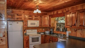 Cocina de cabaña de madera con refrigerador, microondas, estufa y pileta.