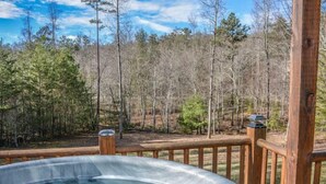 Un jacuzzi en una terraza de madera con vista a un bosque.