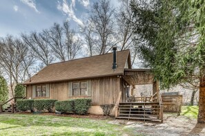 A wooden cabin with a sloped roof, a covered porch, and a small deck.
