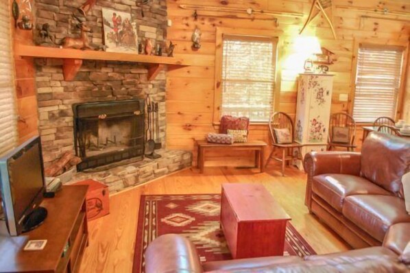 A cozy cabin interior with a fireplace, leather sofa, and wooden walls. - Overlook Retreat (Blue Ridge)