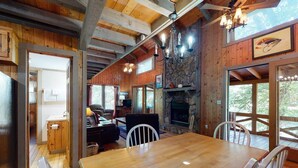 A wooden interior with a dining table, chairs, a fireplace, and a stone wall. - Fish Trap Cabin (Mineral Bluff)