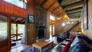 A wooden cabin interior with a stone fireplace, a leather sofa, and a dining area. - Fish Trap Cabin (Mineral Bluff)