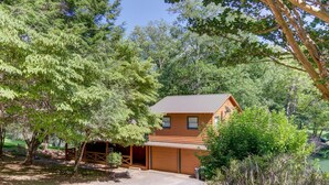 A wooden cabin with a garage, surrounded by trees and a clear sky. - Fish Trap Cabin (Mineral Bluff)