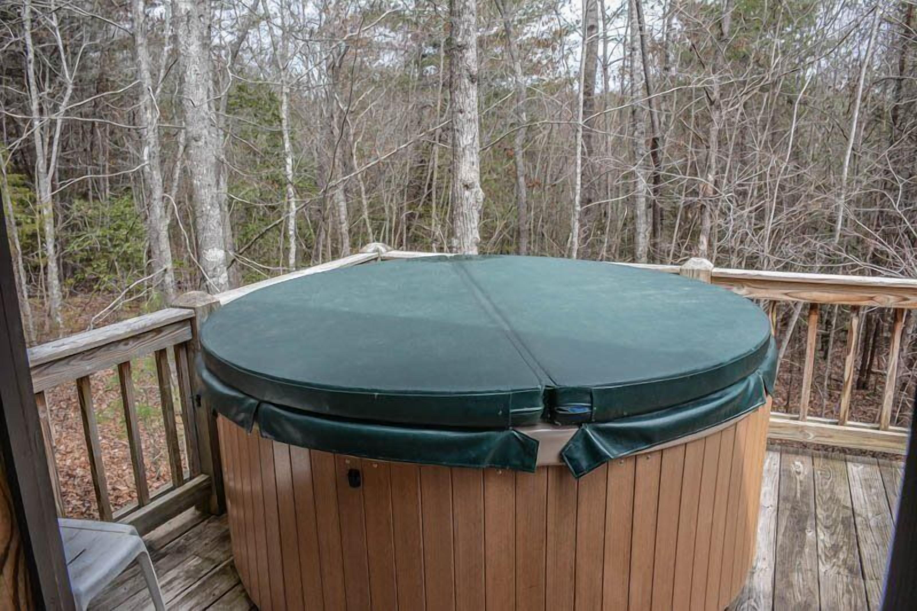 Un jacuzzi en una terraza de madera rodeado de árboles.