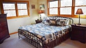 A bedroom with a bed, two nightstands, a dresser, and large windows. - My Mountain Escape (Morganton)