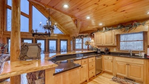 A spacious kitchen with wooden cabinets, a large island, and a view of the outdoors. - Lonesome Dove (Blue Ridge)