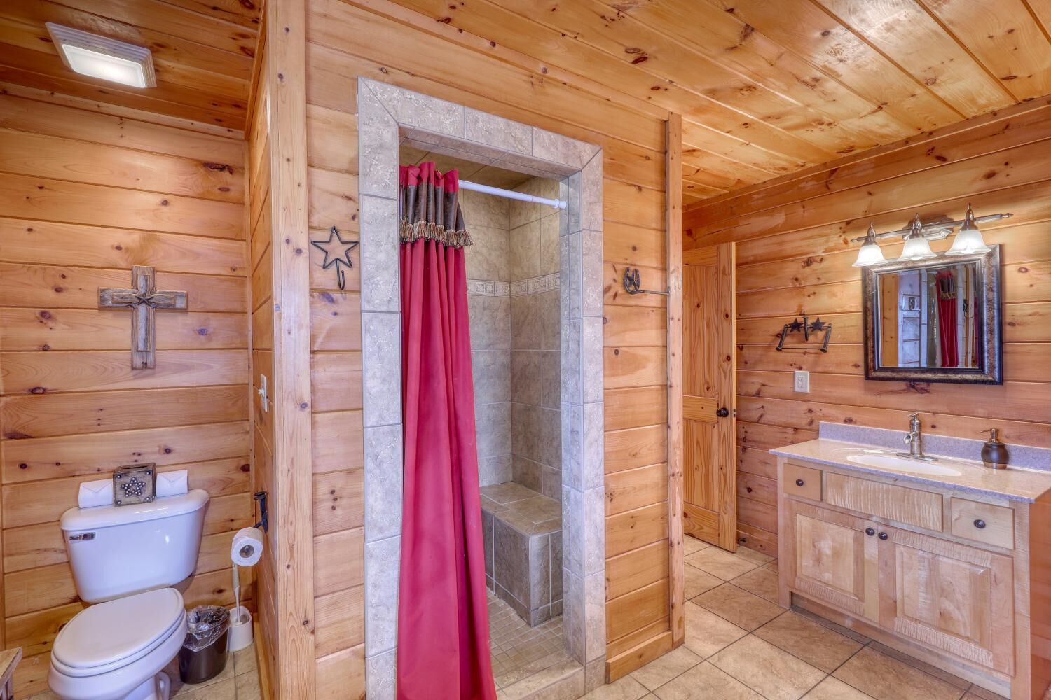 A wooden cabin bathroom with a shower, toilet, and vanity.