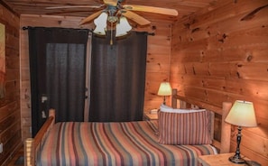 A wooden cabin room with a bed, two bedside lamps, and a ceiling fan. - Cabin Sweet Cabin (Blue Ridge)