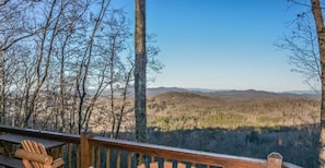 A wooden deck with a view of a forested landscape and distant hills. - Cabin Sweet Cabin (Blue Ridge)