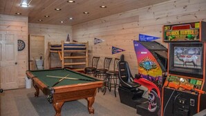 Quarto de madeira com mesa de bilhar, dardos e máquina de pinball.