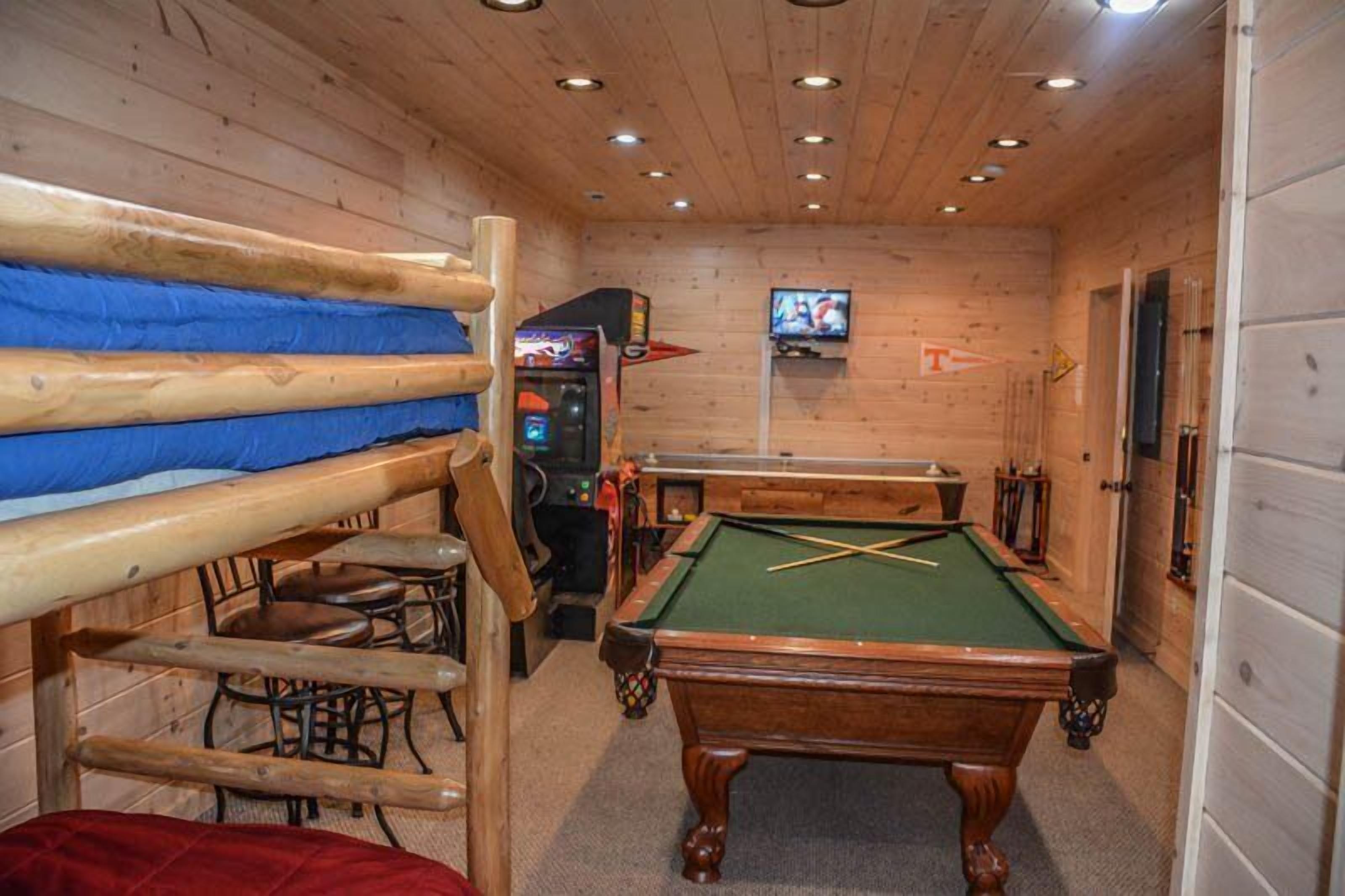 Un interno in legno con letti a castello, un tavolo da biliardo e una televisione.