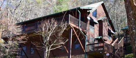 Une cabane avec une façade en bois, un balcon et des fondations en pierre.