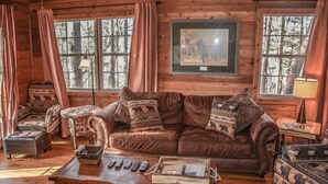 Ein gemütliches Blockhausschlafzimmer mit einer braunen Ledersofa, einem Holztisch und einem gerahmten Bild an der Wand.