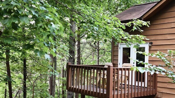 Eine Holzhütte mit einem Balkon mit Blick auf ein bewaldetes Gebiet.