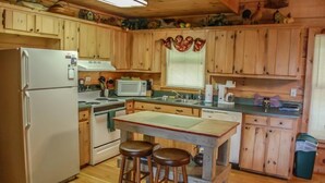 A wooden cabin kitchen with a refrigerator, stove, microwave, sink, and stools. - Into Thin Ayer (Blue Ridge)
