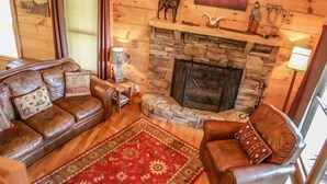 A cozy living room with a stone fireplace, leather sofas, and a red patterned rug. - Into Thin Ayer (Blue Ridge)