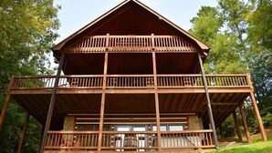 A two-story wooden cabin with a balcony on the upper floor and a covered deck area. - Whitetail Lodge (Mineral Bluff)