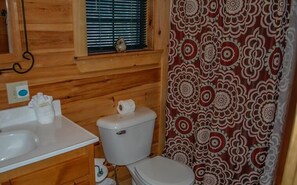 A wooden cabin bathroom with a toilet, sink, and window. - Wolf`s Den (Blue Ridge)