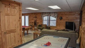 Una habitación acogedora con mesa de juego de discos, paredes de madera, televisor y sofá.
