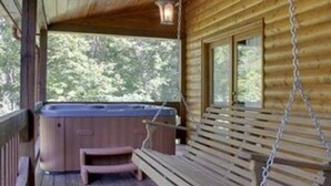 Eine Holzlaube mit Whirlpool, einer Bank und einem Hängestuhl auf der Veranda.