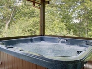 Un bain à remous avec une terrasse en bois et une vue sur les arbres.