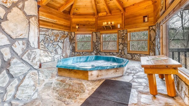 A stone-walled room with a wooden ceiling, a hot tub, and a table. - Twin Peaks 2/malu (Blue Ridge)