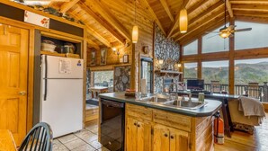 A wooden cabin kitchen with a refrigerator, stove, and dining area. - Twin Peaks 2/malu (Blue Ridge)