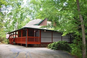 A wooden cabin with a porch, surrounded by trees. - Roosters Roost (Blue Ridge)