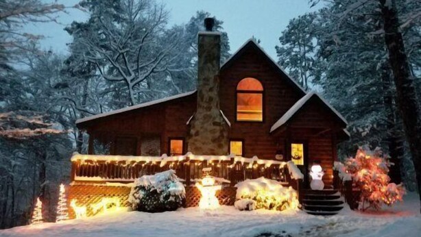 A log cabin with a stone chimney, wooden exterior, and a porch with string lights. - Serendipity (Blue Ridge)