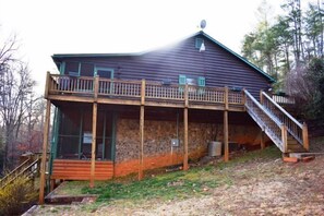 A two-story log cabin with a wooden deck and a staircase leading to the upper level. - Park Hollow (Epworth)