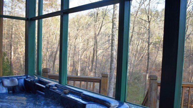 Un jacuzzi con cubierta de madera en el exterior, rodeado de árboles.