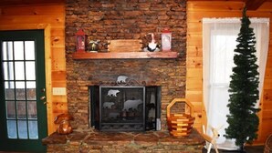 Una chimenea de piedra con repisa, rodeada de paredes de madera y una puerta verde.