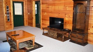 Una habitación con paneles de madera, un televisor sobre un mueble de madera, una pequeña mesa y un armario.