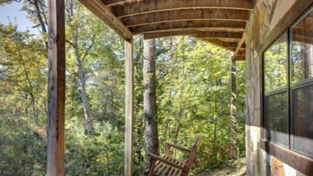 A wooden deck with a swing chair, surrounded by trees. - A Bear Pause (Mineral Bluff)
