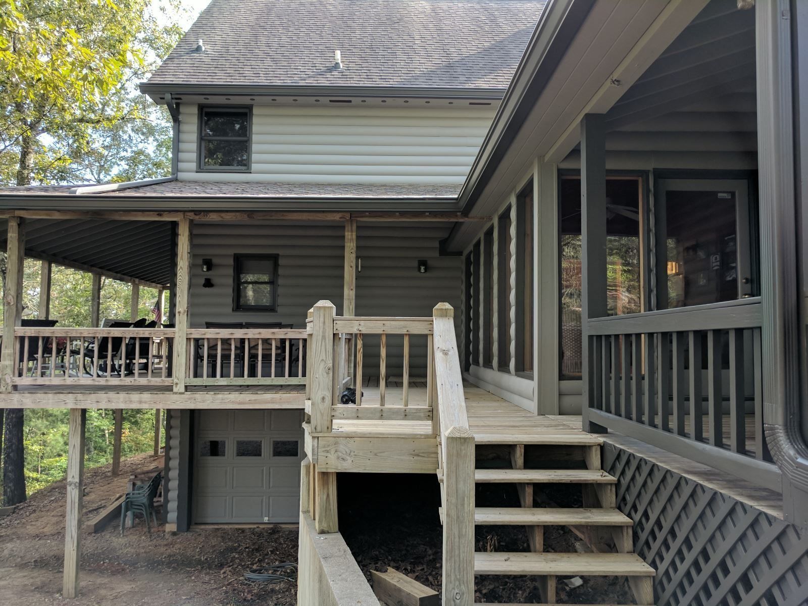 A two-story house with a covered porch and a wooden staircase leading to a deck.