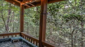A wooden deck with a view of a forested area. - Squirrelled Away (Cherry Log)