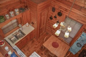 Eine kleine Küche mit Holzausstattung, einem doppelten Waschbecken und einer Pendelleuchte.