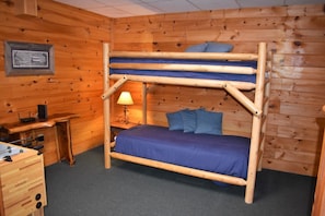 A bunk bed with blue bedding, a desk with a lamp, and a framed picture on the wall.