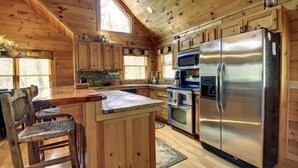 Cocina de cabaña de madera con una isla central, electrodomésticos integrados y un gran ventanal.