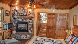 A cozy room with a stone fireplace, wooden ceiling, and a bed with a quilt. - Picabo (Blue Ridge)