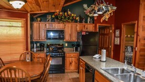 A kitchen with wooden cabinets, a stove, a microwave, a refrigerator, and a sink. - Picabo (Blue Ridge)