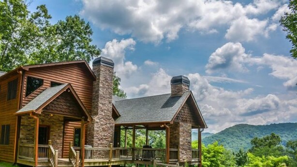 A log cabin with a stone chimney, a porch, and a view of the mountains. - Dream Catcher (Morganton)