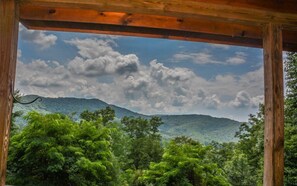 Una pérgola de madera con vistas a un paisaje montañoso y frondosa vegetación verde.