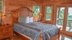 A wooden bedroom with a bed, two bedside tables, and a window. - Dream Catcher (Morganton)