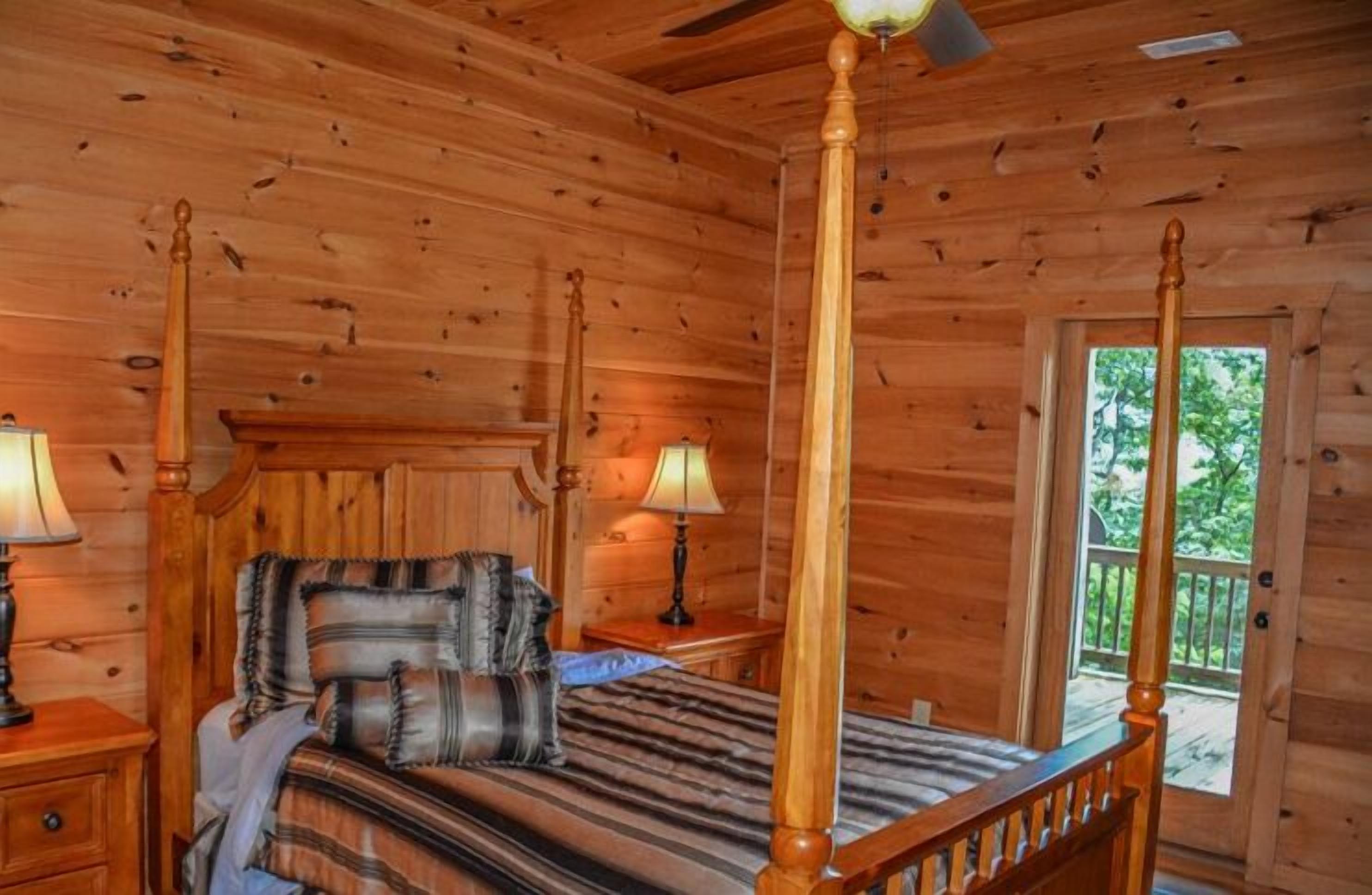 Een houten slaapkamer met een hemelbed, twee bedlampen en een balkondeur.