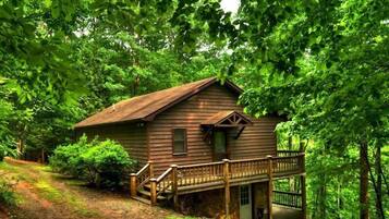 A wooden cabin with a porch and a staircase leading to the entrance.